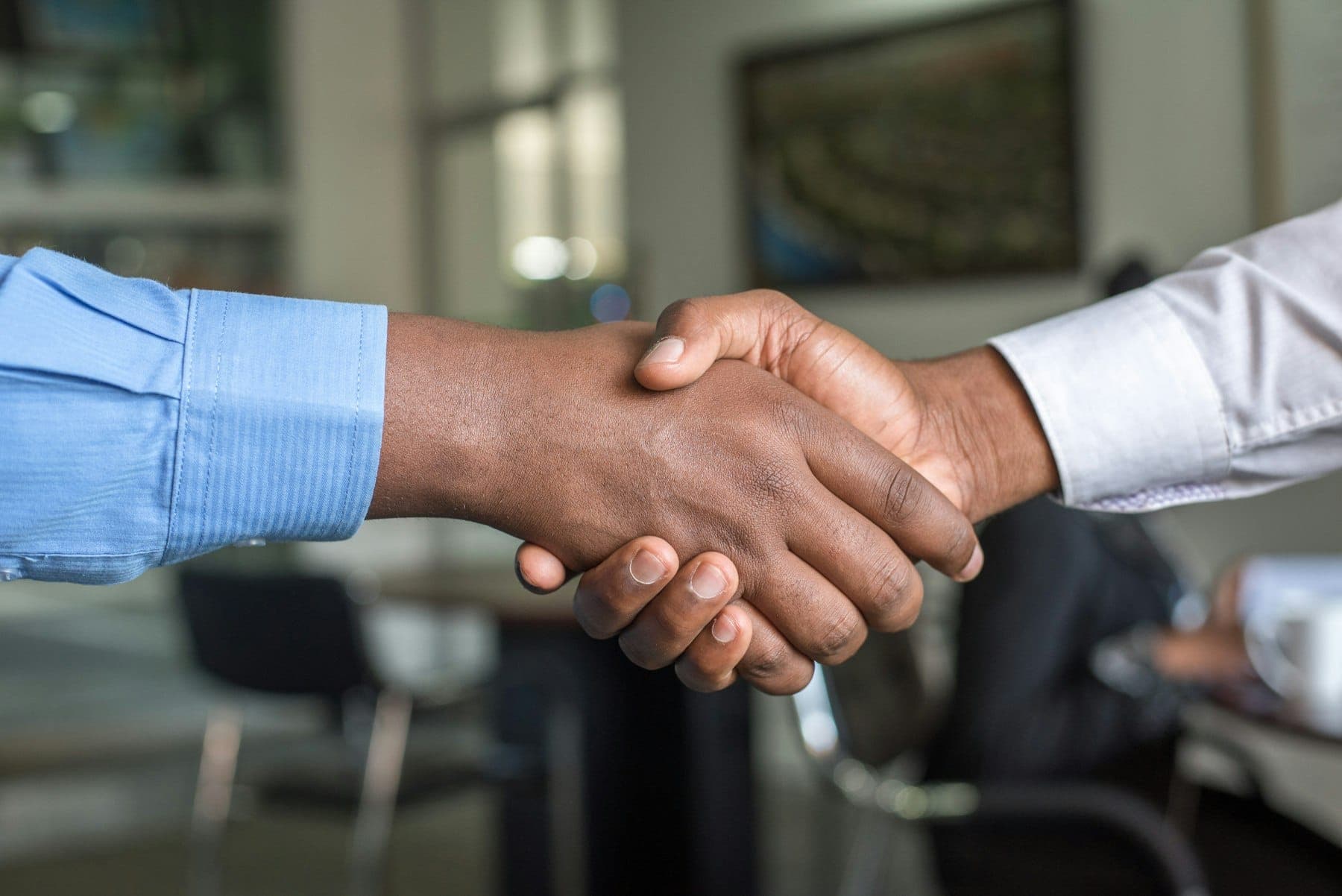 Two business people shaking hands across a desk