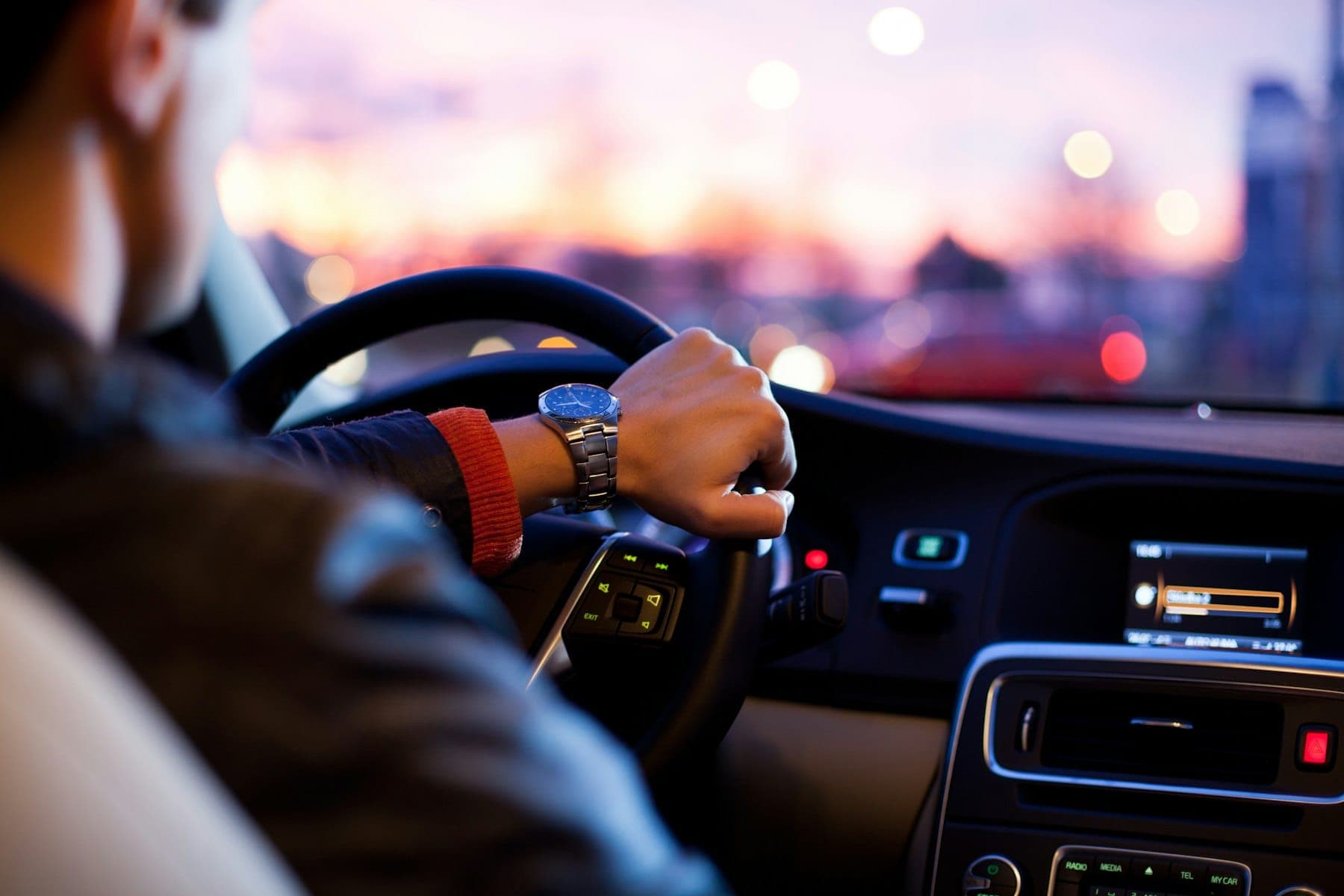 A driver holding a steering wheel at dusk
