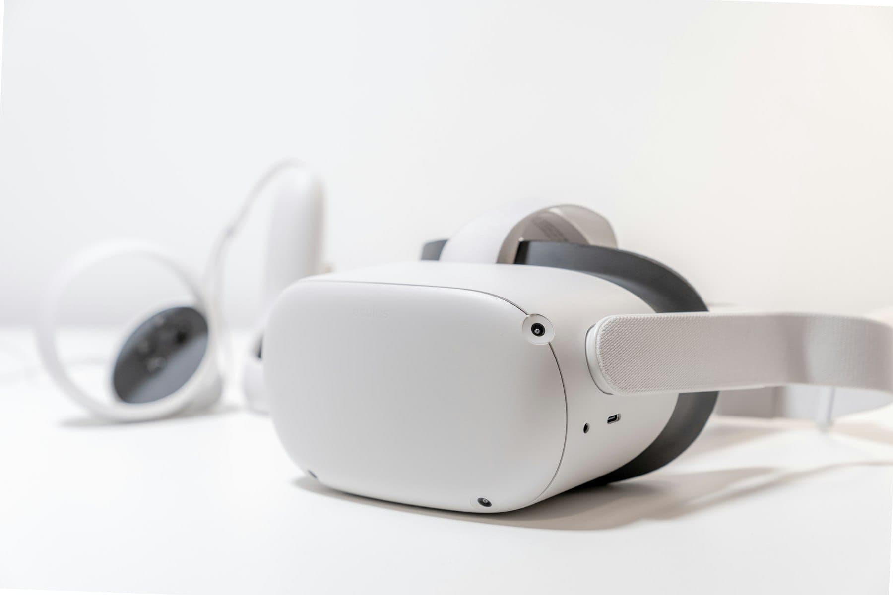 A virtual reality headset and controllers on a white desk